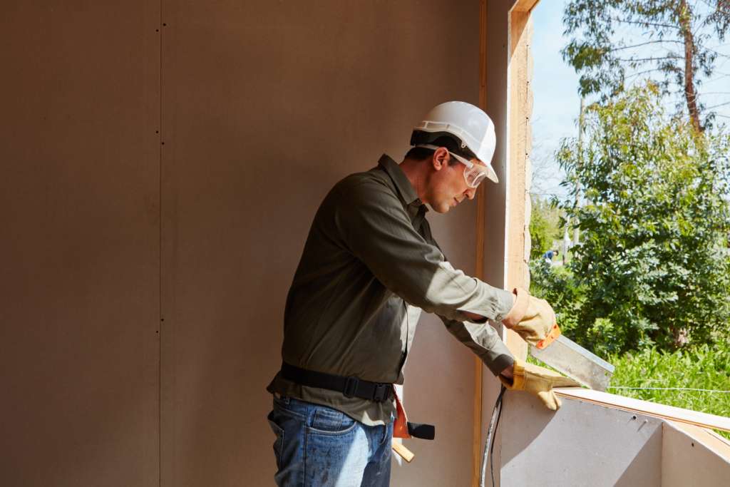 artisan qui scie une planche sur un rebord de fenêtre